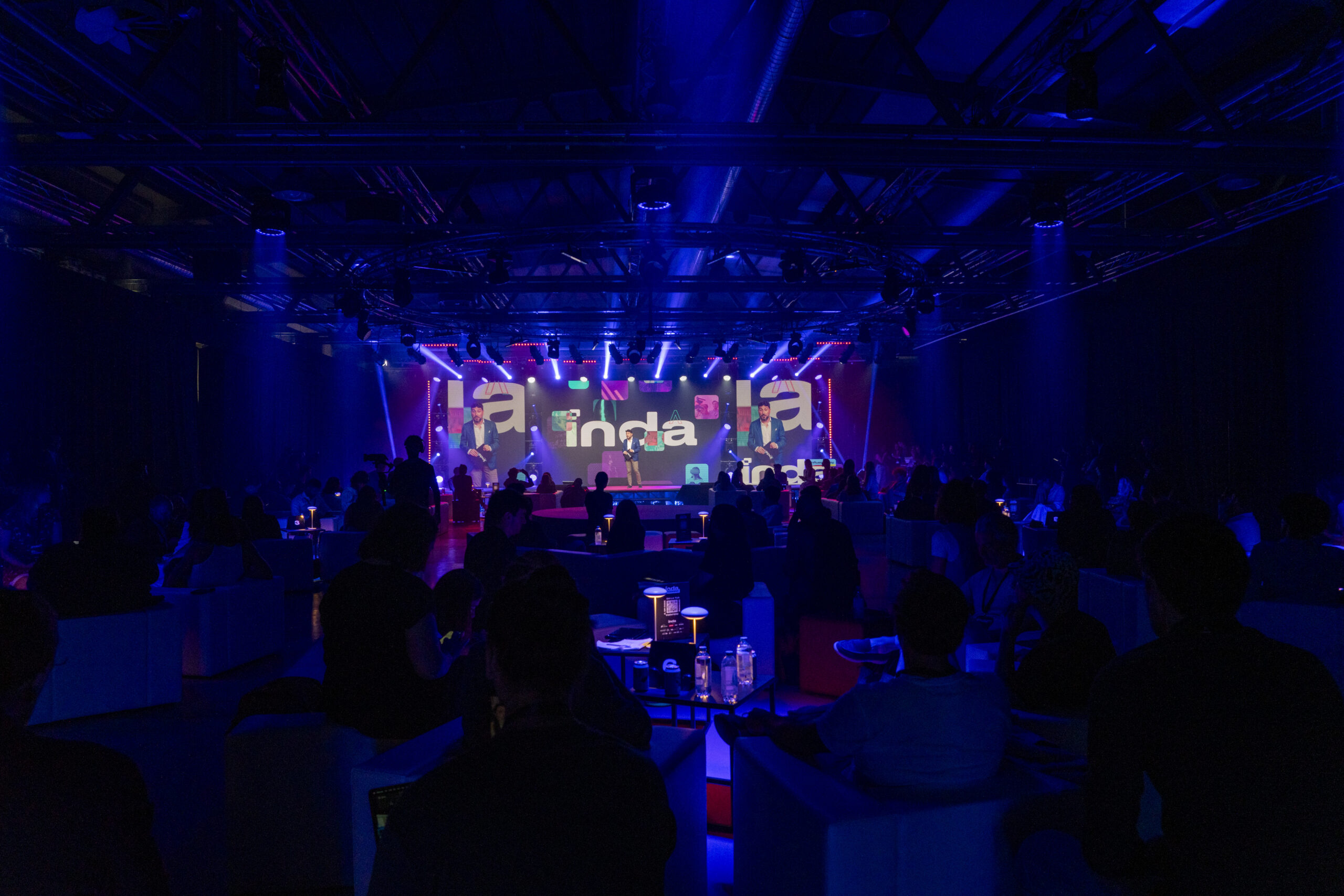 Large conference stage with "INDA" logo, illuminated in blue, showcasing Influence Day 2024 event.